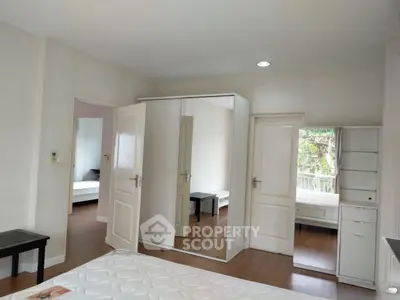 Spacious bedroom with mirrored wardrobe and wooden flooring