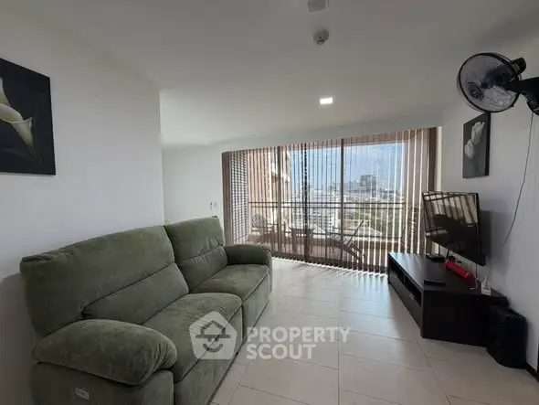 Spacious living room with large windows and city view, featuring a comfortable sofa and modern decor.