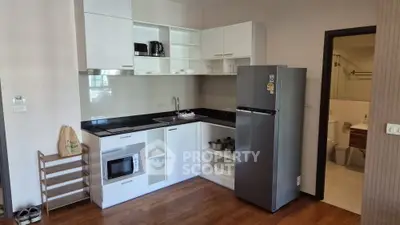 Modern kitchen with sleek appliances and wooden flooring in a cozy apartment setting.