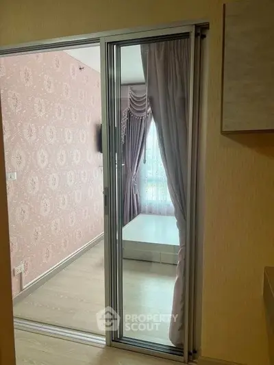 Cozy bedroom with sliding glass door and elegant curtains, featuring a soft pink accent wall.