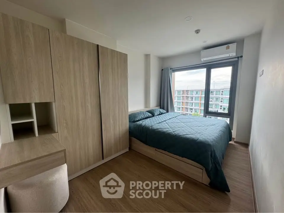 Modern bedroom with large window and stylish wooden furniture in a high-rise apartment.