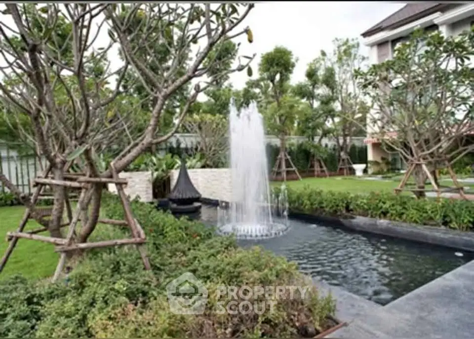 Luxurious garden with elegant fountain and lush greenery in upscale residential complex.