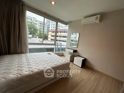 Spacious bedroom with large window and modern decor in urban apartment