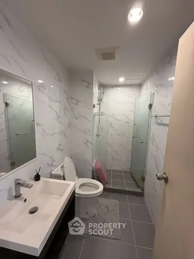 Modern bathroom with sleek design, glass shower, and marble walls in a contemporary home.