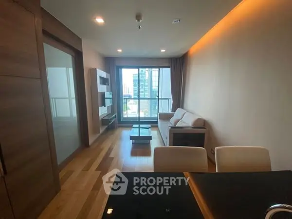 Modern living room with city view, wooden flooring, and stylish furniture in a high-rise apartment.