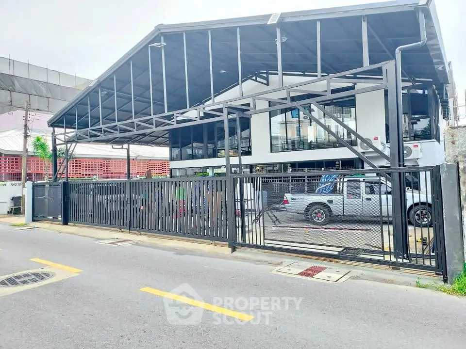 Modern industrial-style building with sleek metal design and spacious parking area.