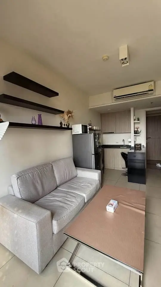 Modern living room with sleek kitchen, cozy sofa, and stylish shelves in open layout apartment.