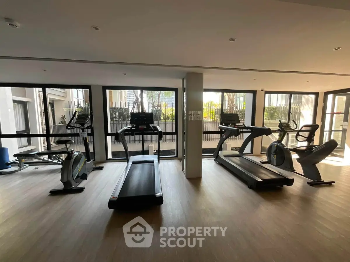 Modern gym with state-of-the-art equipment and large windows offering natural light.