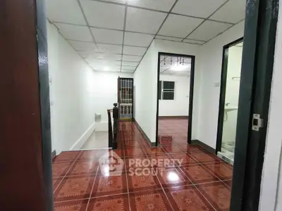 Spacious hallway with polished wooden floors and modern ceiling tiles in a residential property.