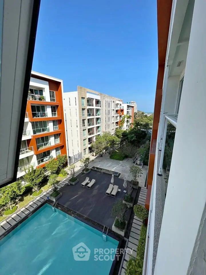 Modern apartment complex with pool and garden view from balcony.