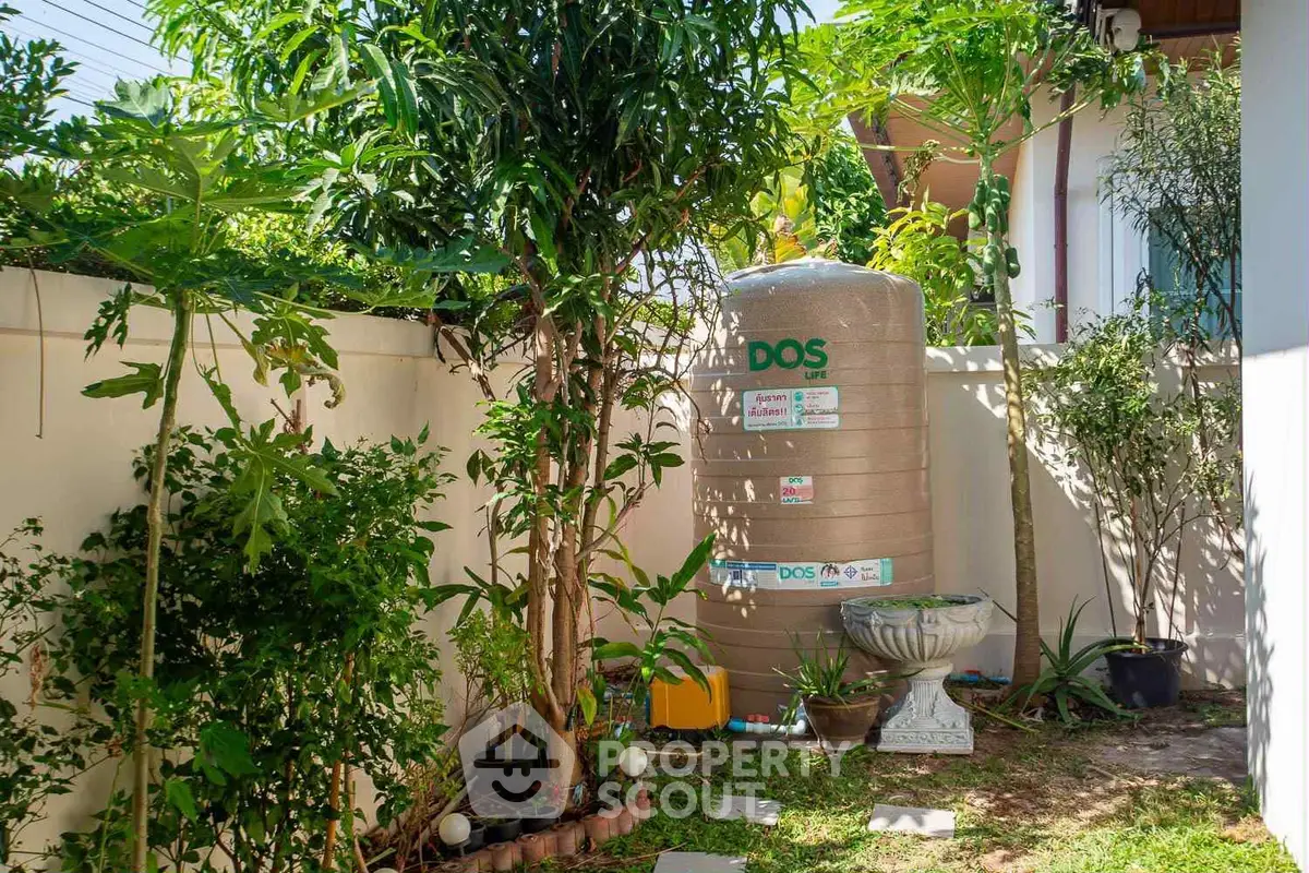 Charming garden corner with water tank and lush greenery, perfect for serene outdoor living.