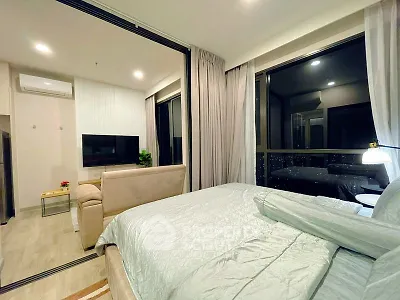 Modern studio apartment with cozy bedroom and living area, featuring large windows and stylish decor.