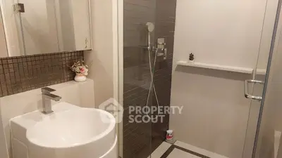 Modern bathroom with sleek shower and stylish sink in contemporary apartment.