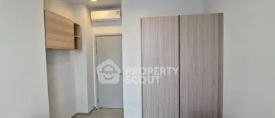 Modern minimalist bedroom with sleek wardrobe and air conditioning unit.