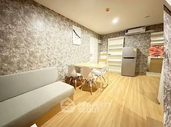 Modern living room with dining area and kitchen, featuring stylish decor and wooden flooring.