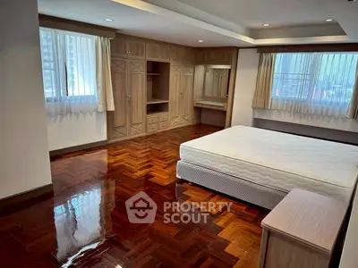 Spacious bedroom with polished wooden floors and built-in wardrobe in a modern apartment.