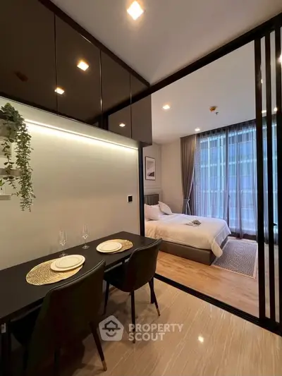 Modern studio apartment with sleek dining area and cozy bedroom, featuring elegant decor and natural light.