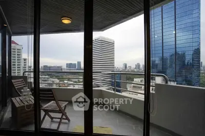 Stunning cityscape view from modern balcony with sleek glass doors and cozy seating.