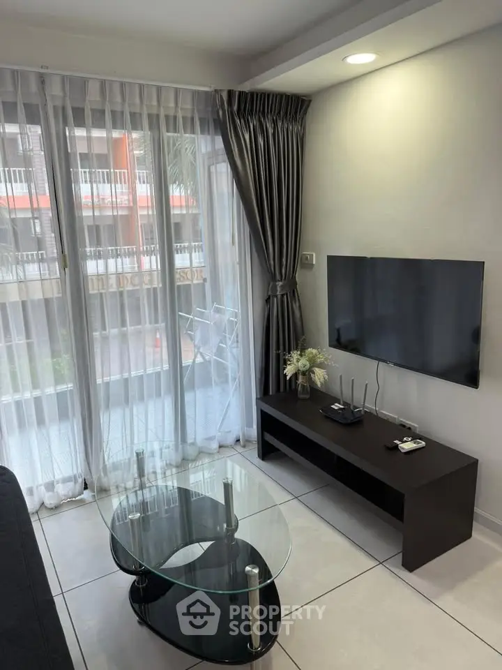 Modern living room with sleek TV setup and glass coffee table, featuring floor-to-ceiling windows and elegant curtains.