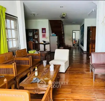 Charming wooden-floored living room with elegant furniture and cozy ambiance, perfect for family gatherings.