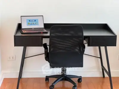 Modern home office setup with sleek black desk and ergonomic chair on wooden floor.