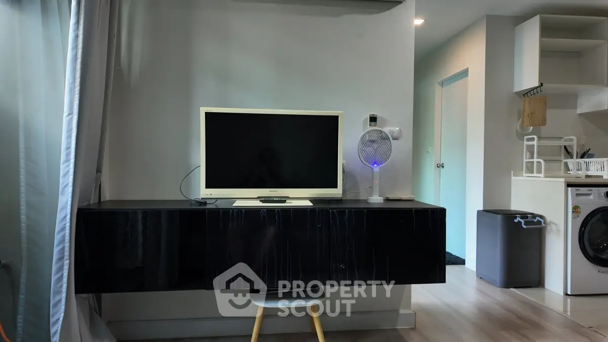 Modern living room with sleek black TV stand and washing machine in open layout.