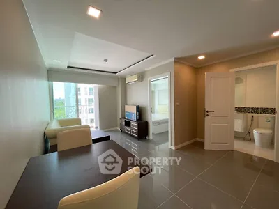 Modern apartment interior with open living and dining area, featuring sleek furniture and natural light.