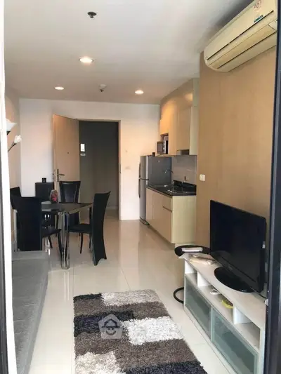 Modern open-plan living room with sleek kitchen and dining area, featuring contemporary furniture and appliances.