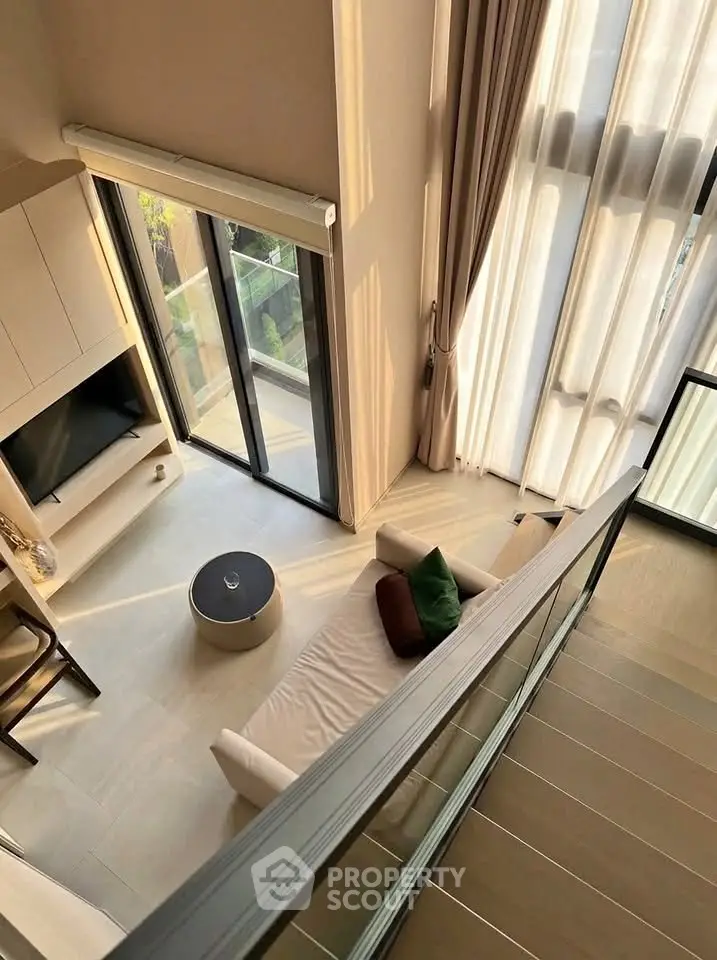 Modern loft-style living room with high ceilings and large windows, offering a bright and airy atmosphere.