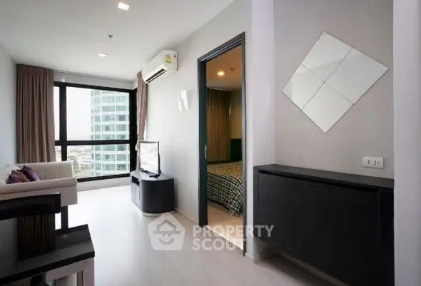 Modern apartment interior with living room and bedroom view, featuring sleek furniture and large windows.