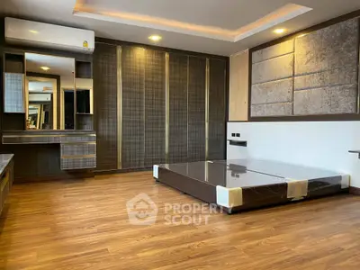 Spacious modern bedroom with wooden flooring and built-in wardrobe