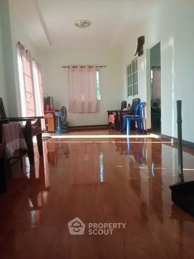 Spacious living room with glossy wooden floors and natural light