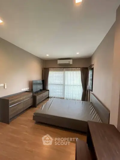 Spacious bedroom with modern furnishings and large window for natural light.