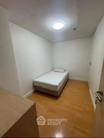 Cozy minimalist bedroom with single bed and wooden flooring, perfect for a peaceful retreat.