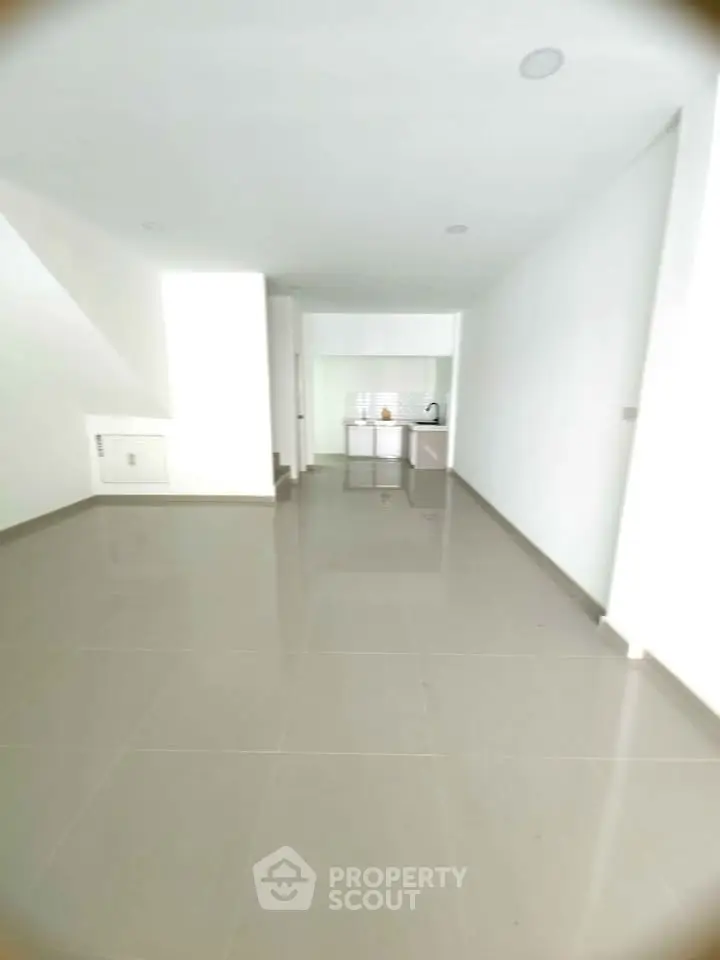 Spacious open-plan living area with sleek tiled flooring and modern kitchenette.