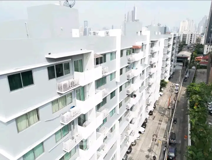 Modern white apartment building with balconies in urban setting