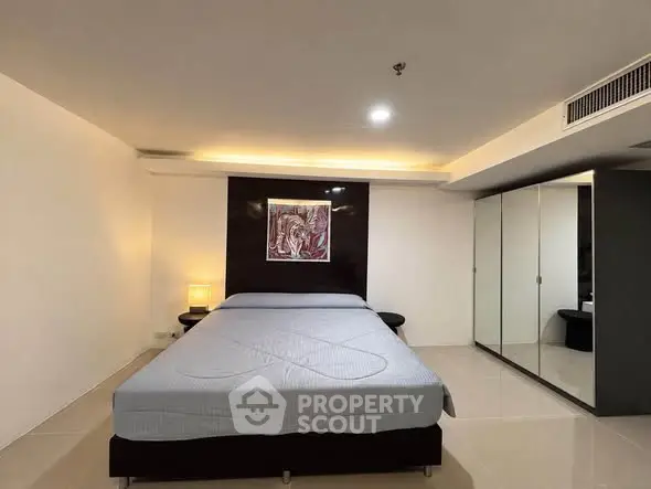 Spacious modern bedroom with sleek design and mirrored wardrobe