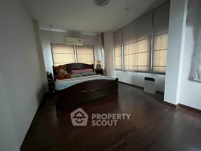 Spacious bedroom with wooden flooring and large windows for natural light.