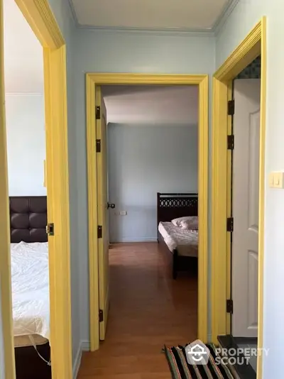 Charming multi-room view showcasing a cozy bedroom with a classic bed frame, set in a home with vibrant yellow door frames and soothing blue walls.