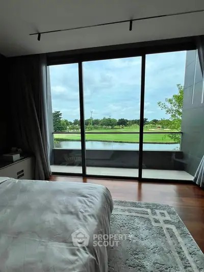 Luxurious bedroom with stunning golf course view through floor-to-ceiling windows.