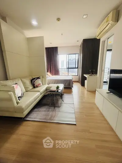 Modern open-plan living room and bedroom with stylish decor and city view.