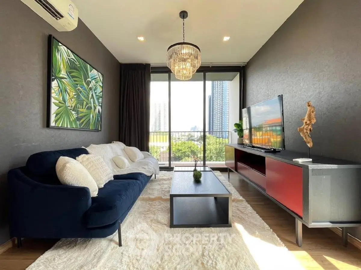 Stylish living room with modern decor and city view, featuring a plush sofa and elegant chandelier.