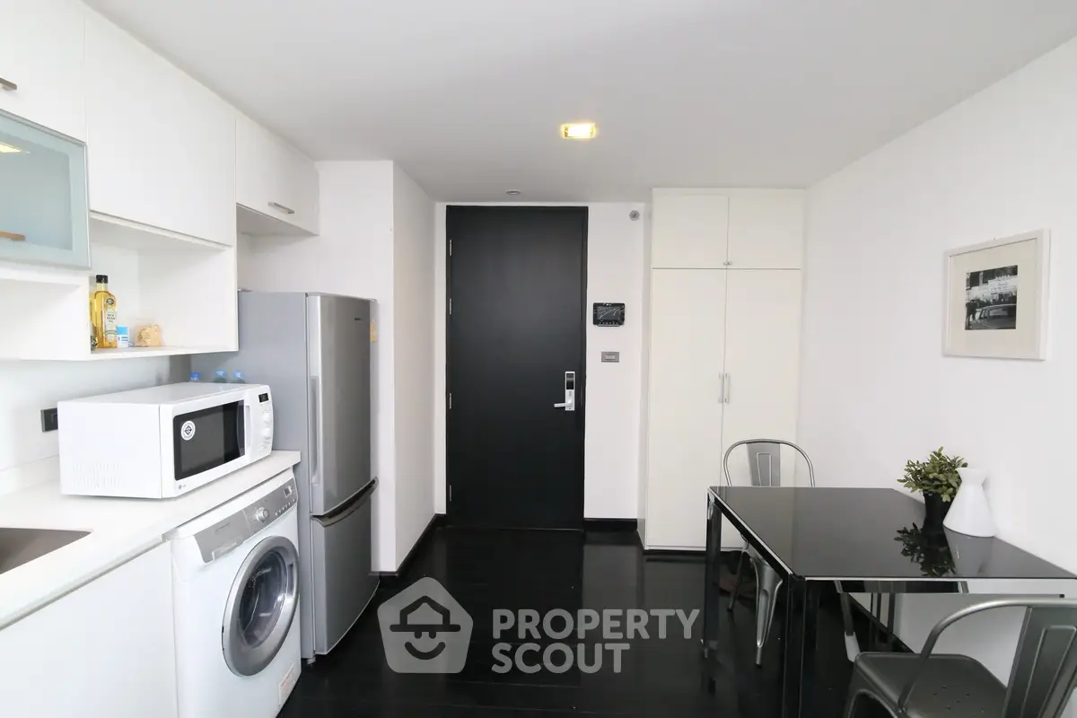 Modern kitchen with sleek appliances and dining area in contemporary apartment.