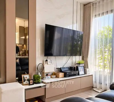 Modern living room with sleek TV setup and large window for natural light.