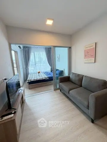 Modern living room with cozy sofa and TV, adjacent to a stylish bedroom with large windows.