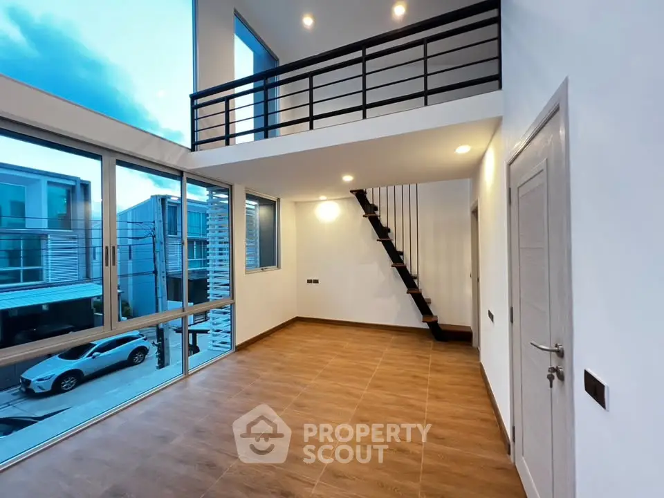 Modern duplex interior with high ceilings and large windows offering natural light and street view.