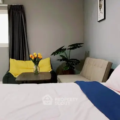 Cozy bedroom with modern decor, featuring a comfortable bed, stylish seating area, and vibrant floral arrangement.