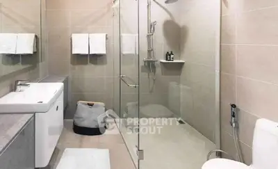 Modern bathroom with glass shower, sleek fixtures, and neutral tiles.