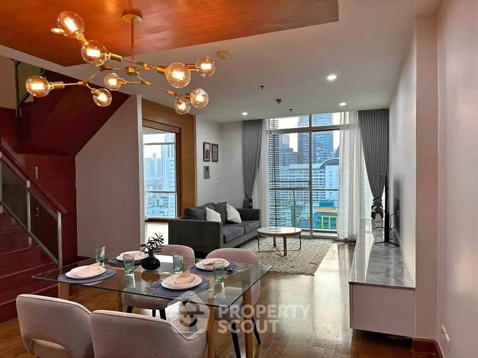 Modern living room with stylish chandelier and city view, featuring a cozy dining area and sleek furniture.