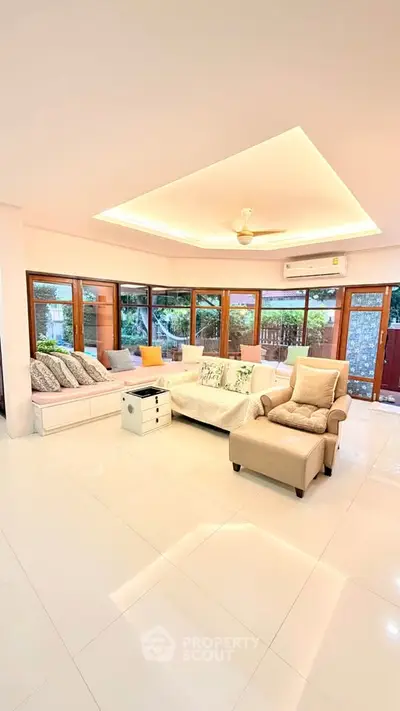 Spacious living room with modern furniture and large windows overlooking a lush garden.